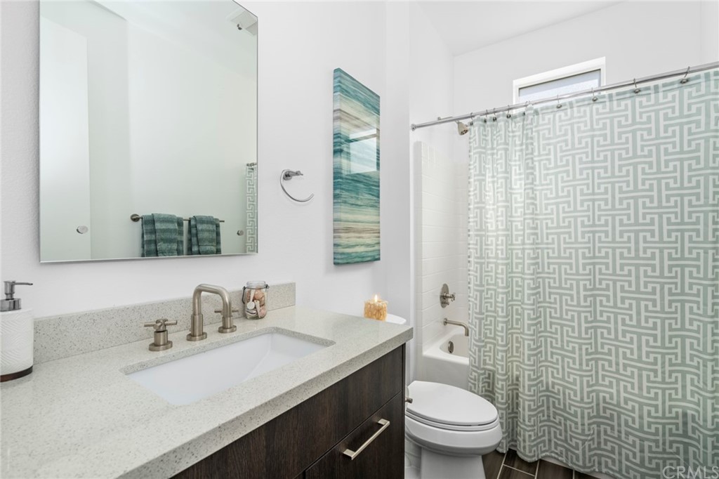 1267 Westreef Costa Mesa, CA 92627 - Photo 16 of 34 a bathroom with a granite countertop sink toilet a mirror and shower curtain