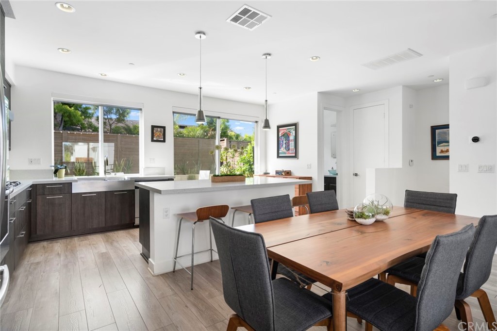 1267 Westreef Costa Mesa, CA 92627 - Photo 8 of 34 a kitchen with stainless steel appliances granite countertop a kitchen island hardwood floor sink stove dining table and chairs