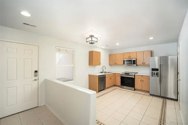 a large kitchen with a refrigerator a stove top oven and a sink