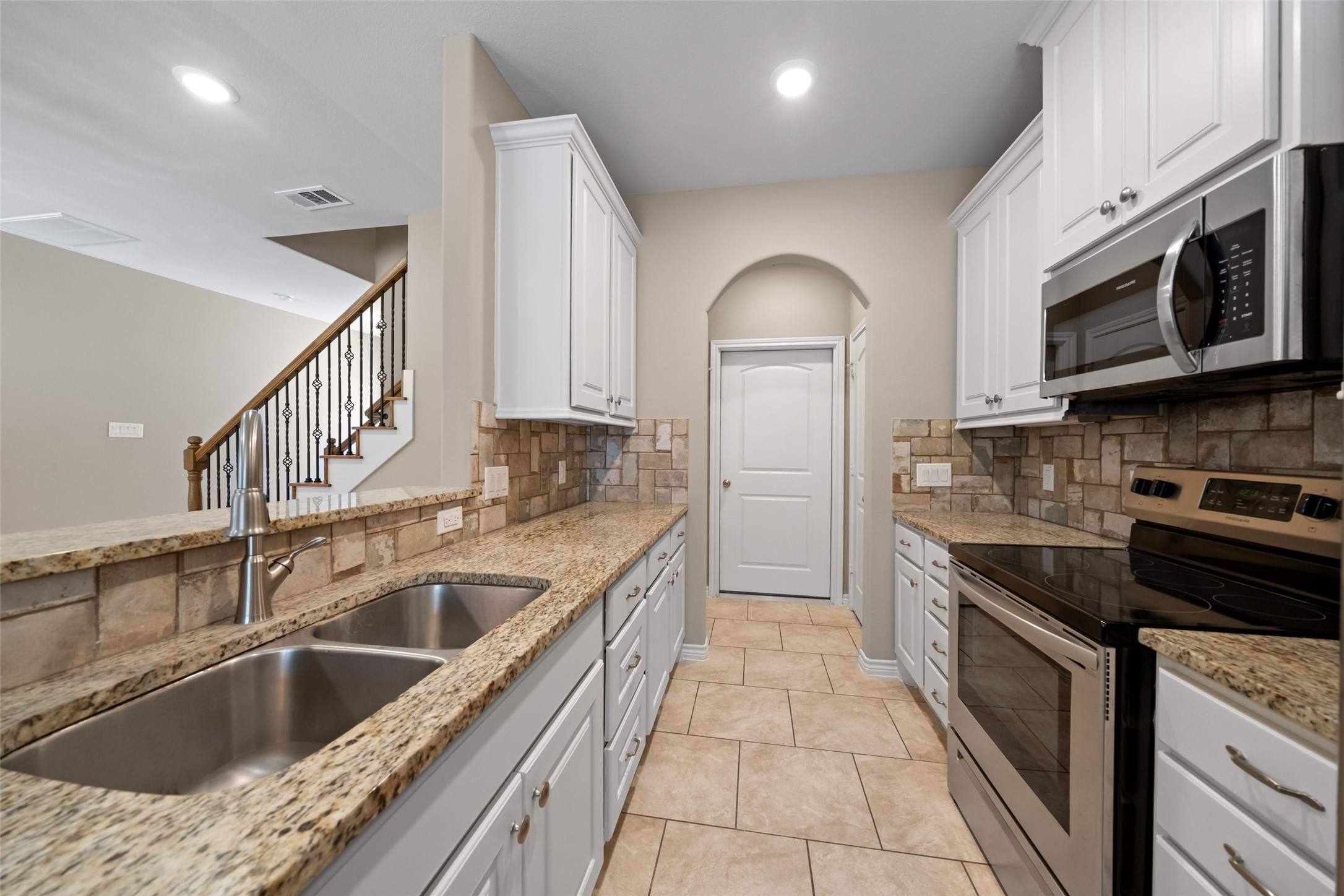 1413 East April Villa, Unit B Conroe, TX 77356 - Photo 10 of 33 a kitchen with stainless steel appliances granite countertop a sink a microwave and stove