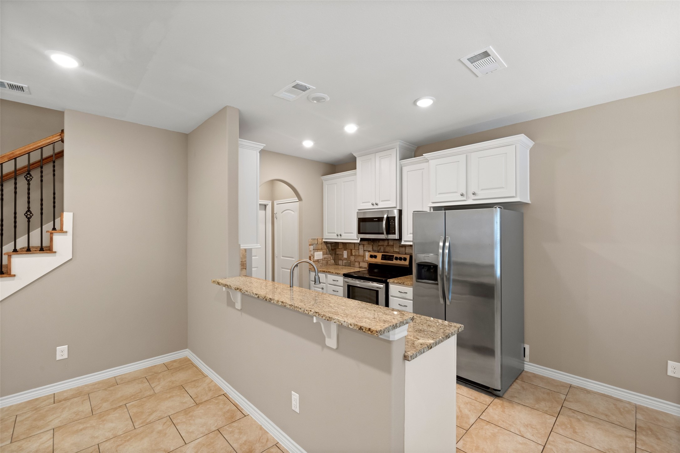 1413 East April Villa, Unit B Conroe, TX 77356 - Photo 12 of 33 a kitchen with stainless steel appliances a refrigerator sink and microwave