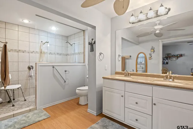 a spacious bathroom with a double vanity sink a mirror and a toilet