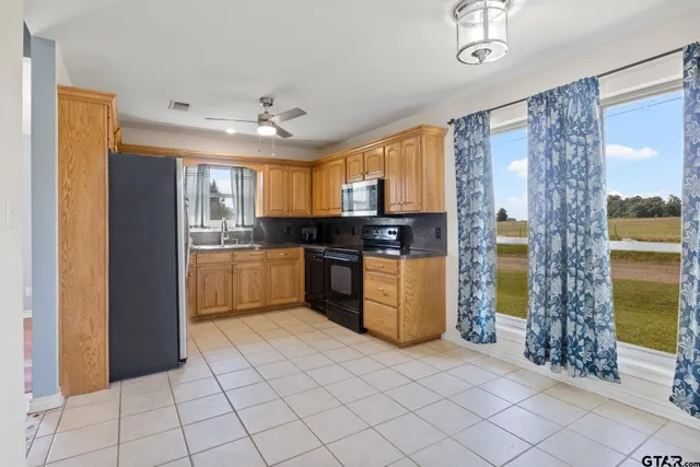 a kitchen with stainless steel appliances granite countertop a refrigerator a sink dishwasher and white cabinets with wooden floor