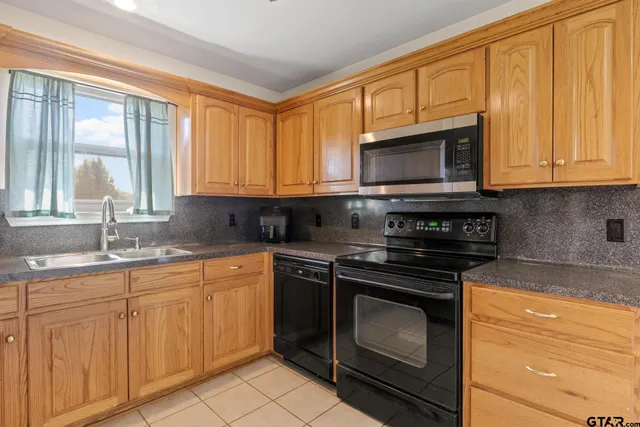 a kitchen with granite countertop a stove sink and microwave