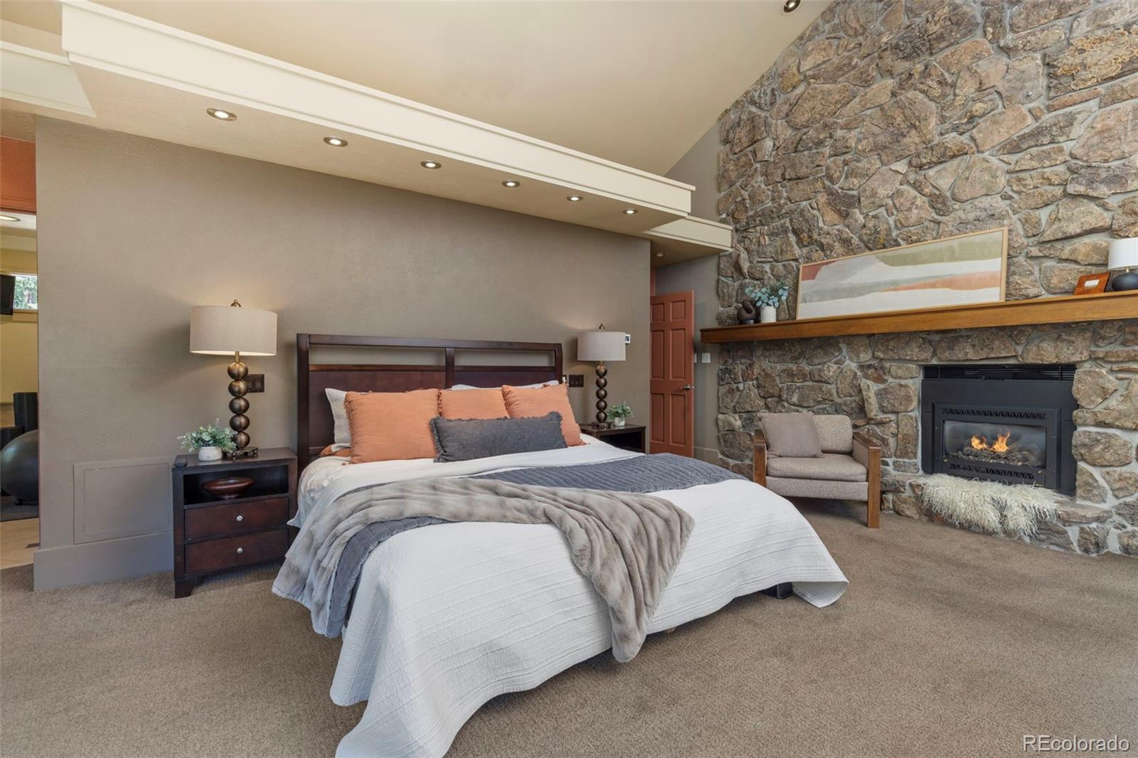 1323 South Snyder Gulch Road Evergreen, CO 80439 - Photo 17 of 47 a bedroom with a bed and a fireplace