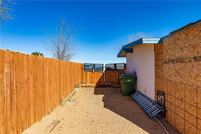 a view of a backyard with wooden fence and a potted plant