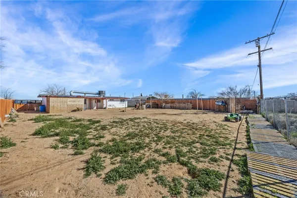 a view of a dry yard with wooden fence