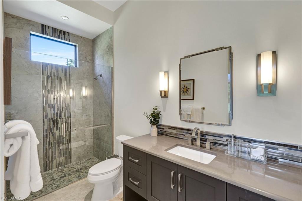 4431 Wayside Drive Naples, FL 34119 - Photo 42 of 49 a bathroom with a granite countertop sink toilet a mirror and shower