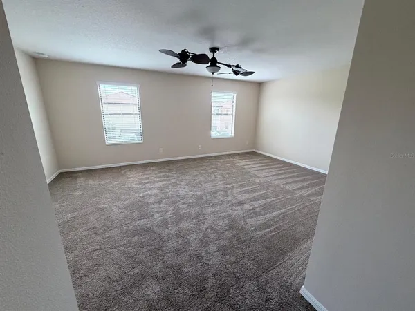 an empty room with windows and ceiling fan