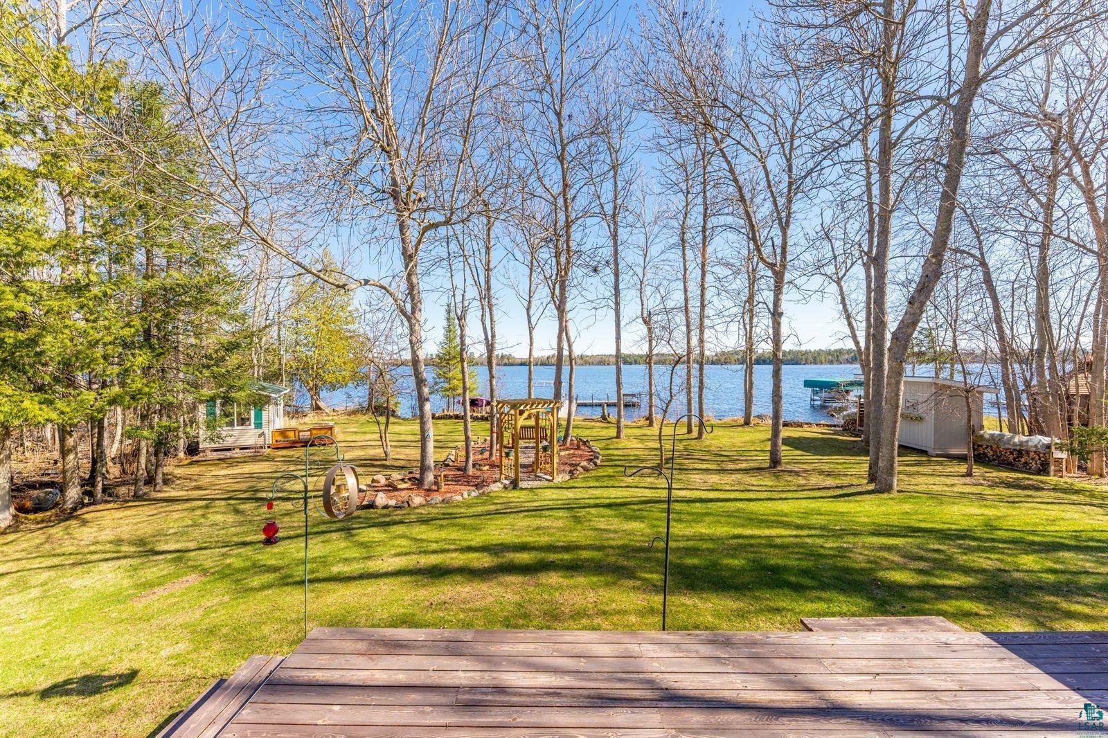 4452 Moccasin Point Road Tower, MN 55790 - Photo 42 of 44 Expansive waterfront property featuring a wood-finish deck, mature trees, a manicured lawn, and a private dock with a boat lift
