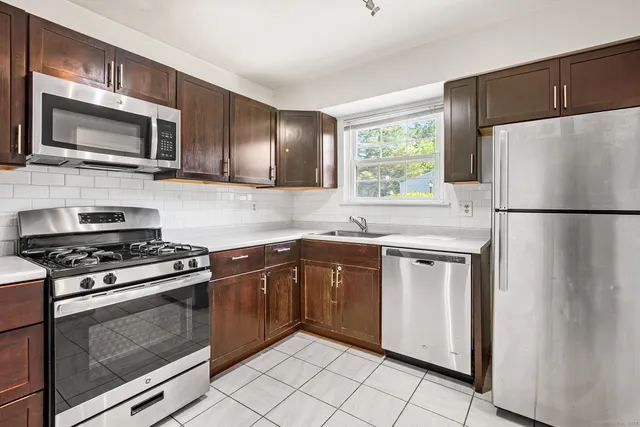 a kitchen with stainless steel appliances granite countertop a refrigerator stove a sink dishwasher and microwave