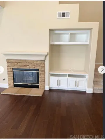 an empty room with wooden floor fireplace and windows