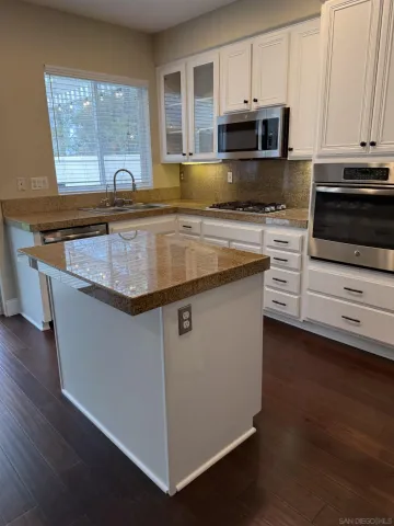 a kitchen with kitchen island granite countertop a stove and a sink