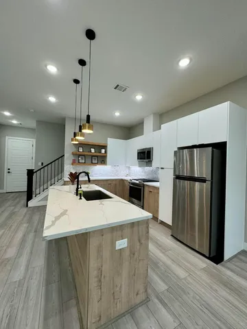 a large kitchen with stainless steel appliances kitchen island a large counter top and wooden floors