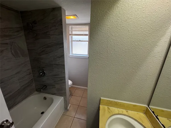 a bathroom with a granite countertop sink a toilet and bathtub