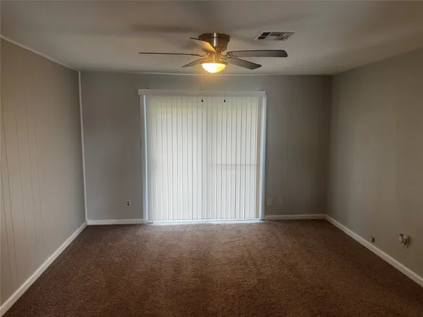 an empty room with a ceiling fan and window