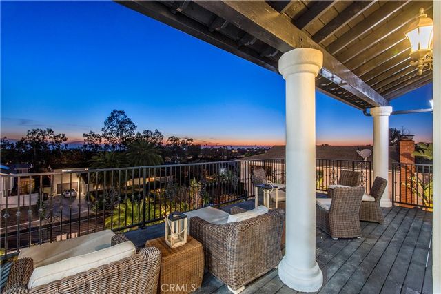 a roof deck with table and chairs potted plants with wooden floor and fence