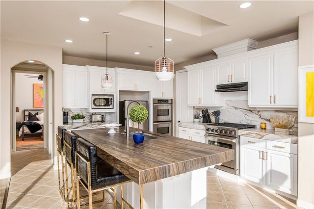 a kitchen with stainless steel appliances kitchen island granite countertop a stove a sink a refrigerator a stove a dining table and chairs with wooden floor