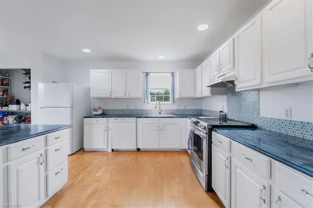 a kitchen with granite countertop white cabinets white stainless steel appliances and sink
