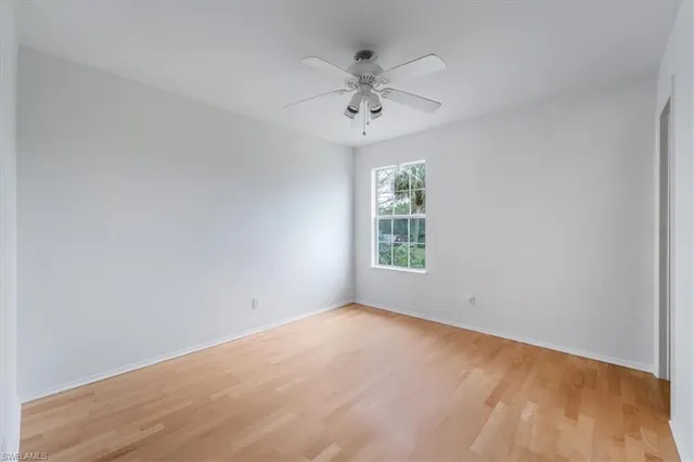an empty room with a window and a fan