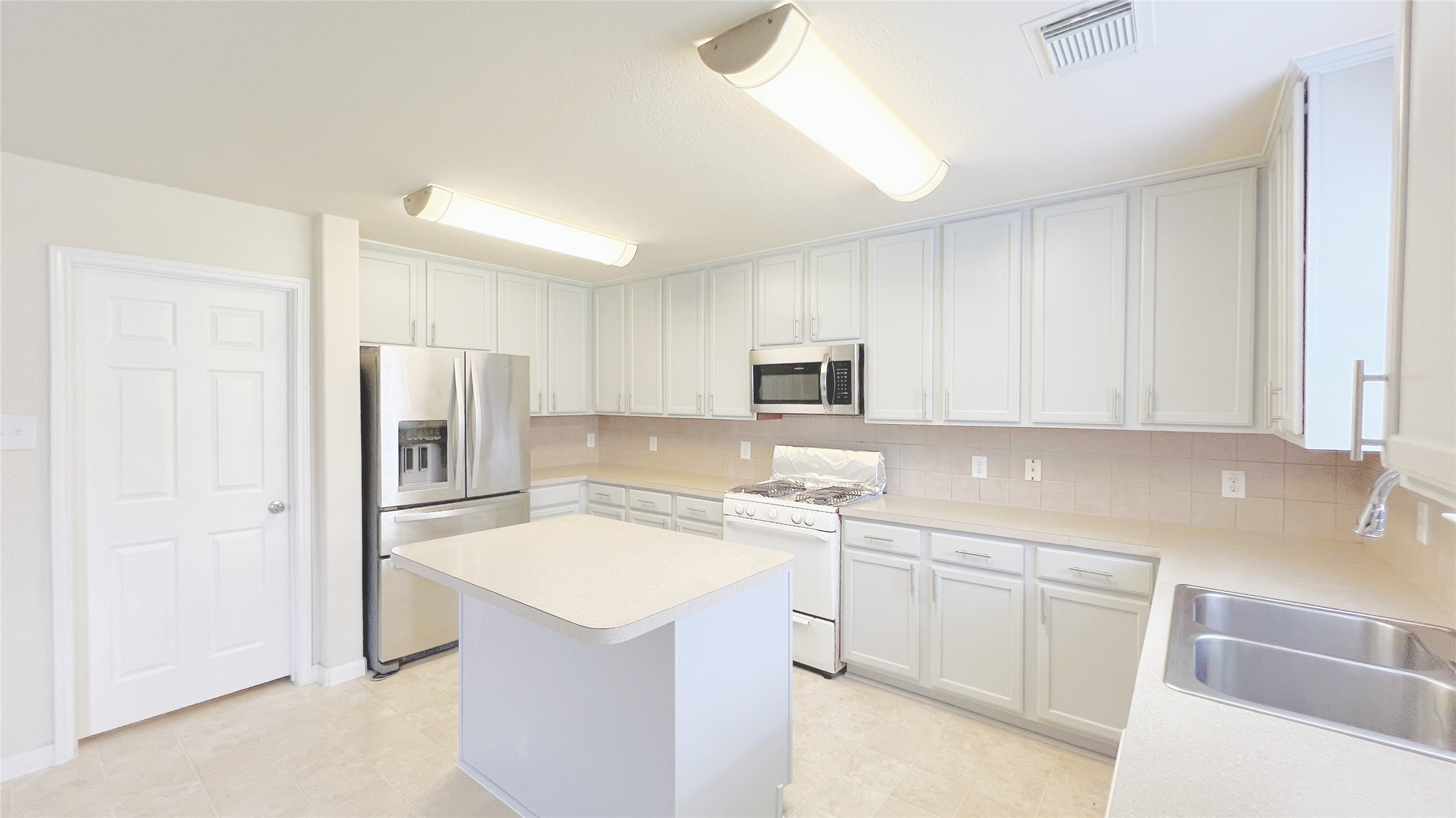 21338 Bella Mountain Drive Spring, TX 77379 - Photo 6 of 33 a kitchen with a sink a refrigerator and white cabinets