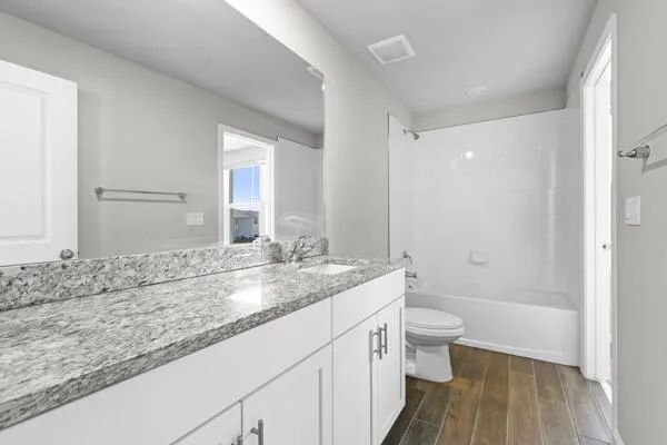 a bathroom with a granite countertop sink a toilet and shower
