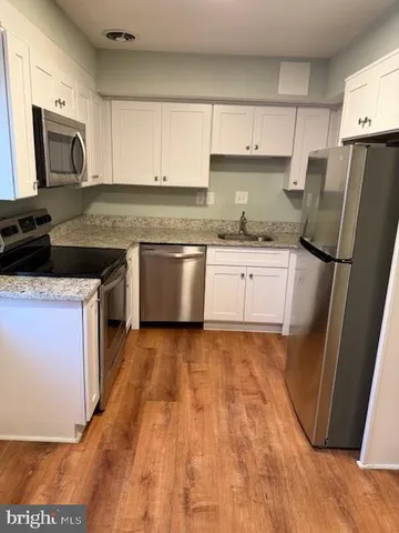 a kitchen with granite countertop a refrigerator a sink a stove top oven a counter space and cabinets