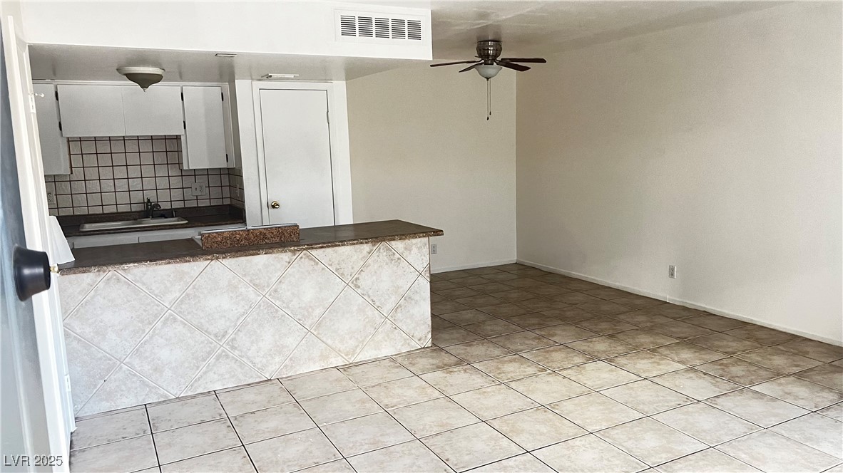 1441 Dorothy Avenue, Unit 2 Las Vegas, NV 89119 - Photo 6 of 20 Kitchen featuring dark countertops, light tile patterned flooring, a ceiling fan, tasteful backsplash, and white cabinets