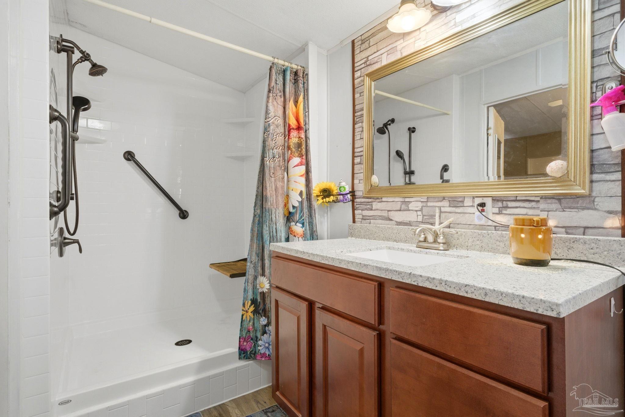 8962 Bluebell Street Milton, FL 32583 - Photo 19 of 35 a bathroom with a granite countertop sink a mirror and a bathtub