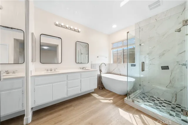 a spacious bathroom with double vanity a toilet a a mirror a bathtub and shower