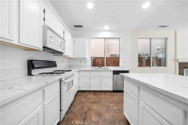 a kitchen with granite countertop white cabinets and white appliances