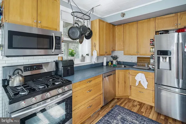 a kitchen with stainless steel appliances granite countertop a stove a refrigerator a sink dishwasher and white cabinets with wooden floor