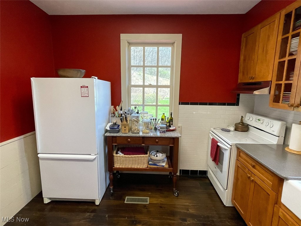 80725 Mallarnee Road Freeport, OH 43973 - Photo 9 of 29 Kitchen with white appliances, under cabinet range hood, dark wood-type flooring, brown cabinetry, and a wainscoted wall