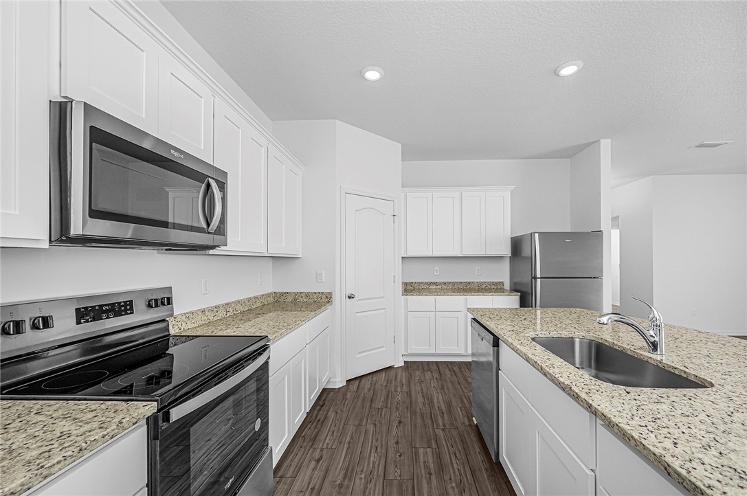 7926 105th Avenue Vero Beach, FL 32967 - Photo 9 of 18 a kitchen with granite countertop a sink dishwasher stove and oven with wooden floor