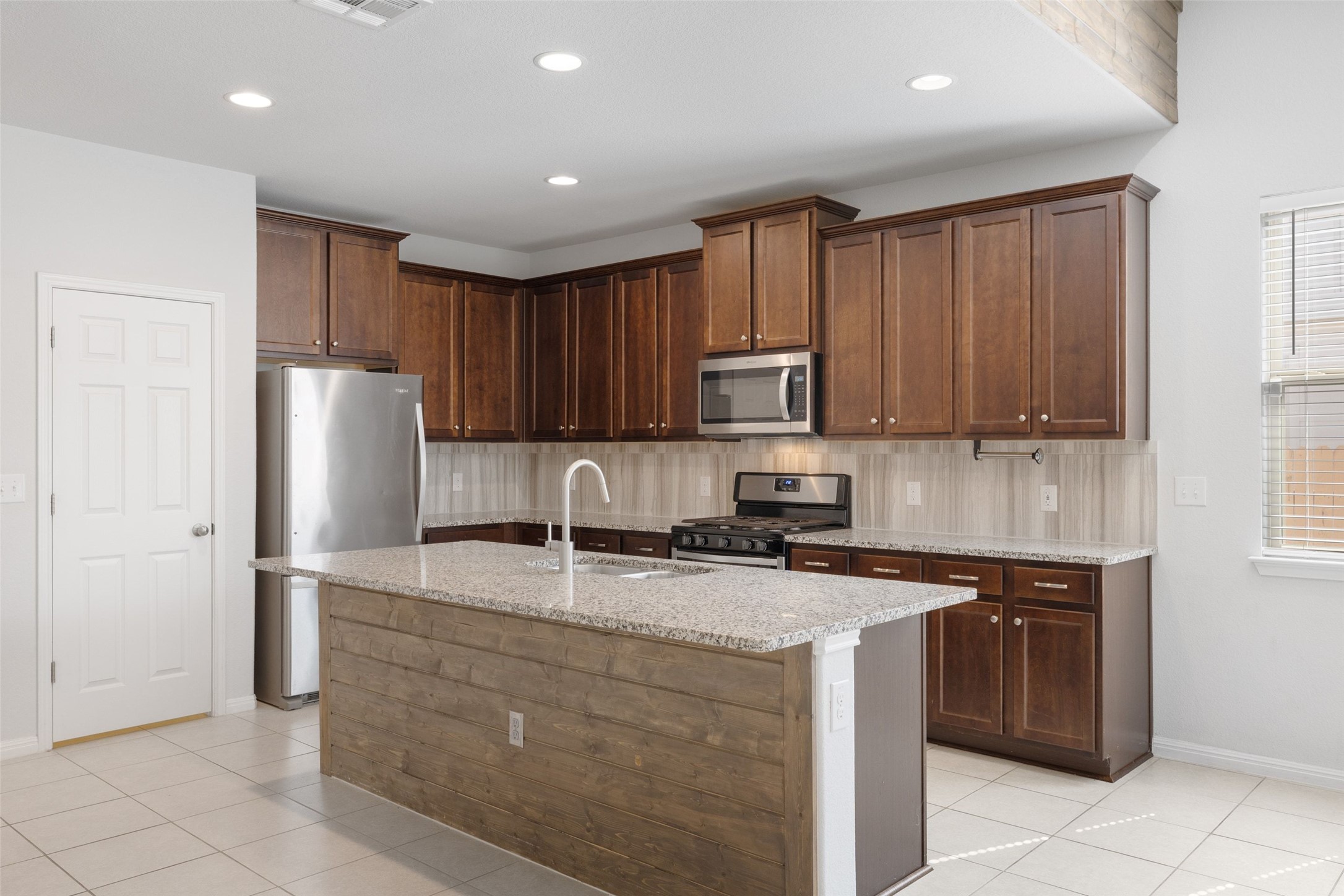 183 Concho Creek Loop Leander, TX 78641 - Photo 8 of 35 a kitchen with kitchen island granite countertop stainless steel appliances a stove a sink a refrigerator and cabinets