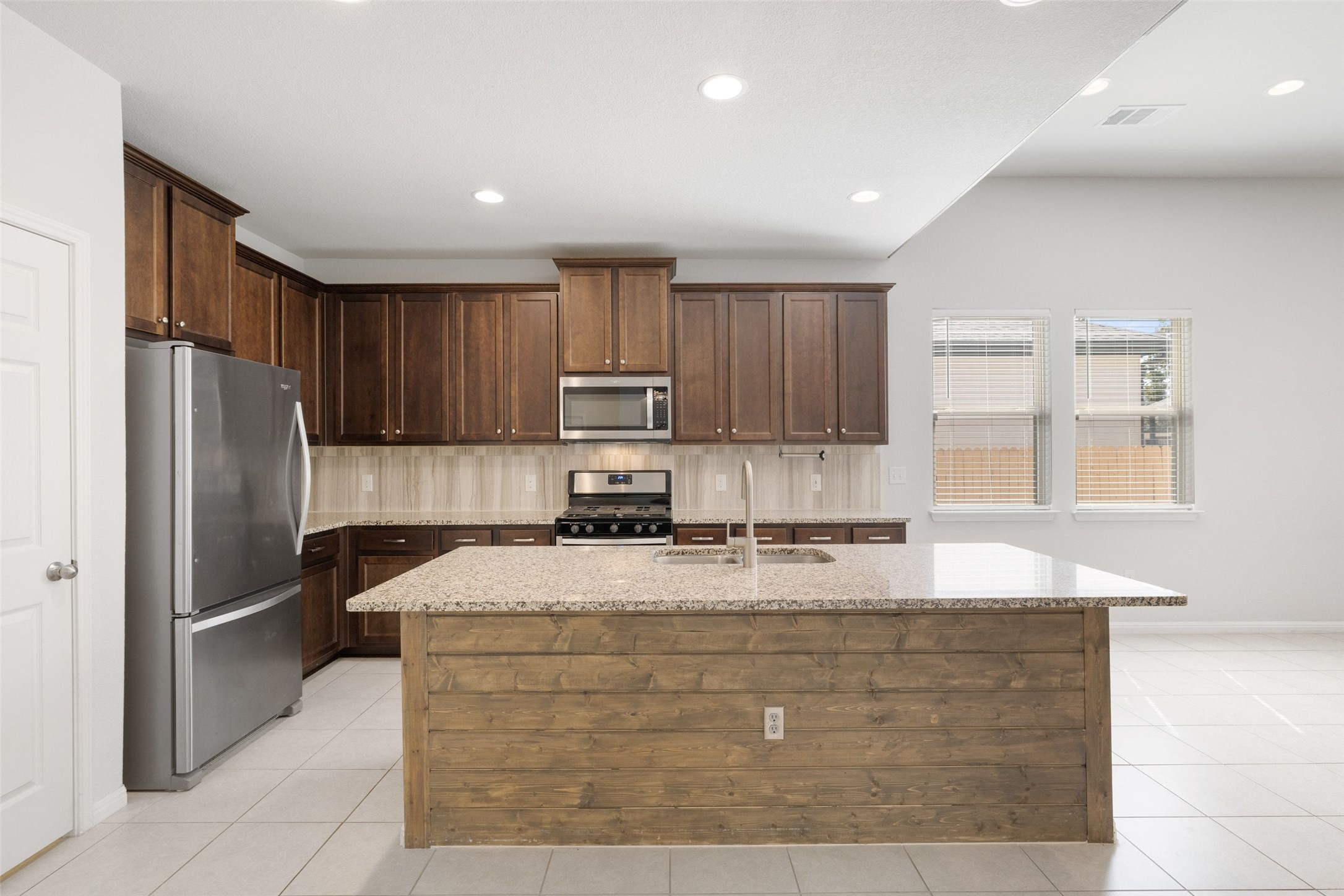 183 Concho Creek Loop Leander, TX 78641 - Photo 9 of 35 a kitchen with kitchen island granite countertop cabinets and refrigerator