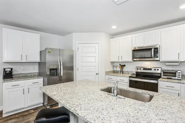 a kitchen with stainless steel appliances granite countertop a stove a sink a refrigerator a microwave and cabinets