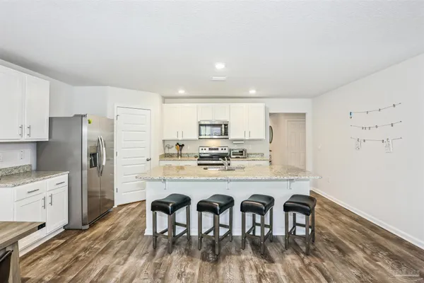 a kitchen with stainless steel appliances a dining table chairs refrigerator and sink