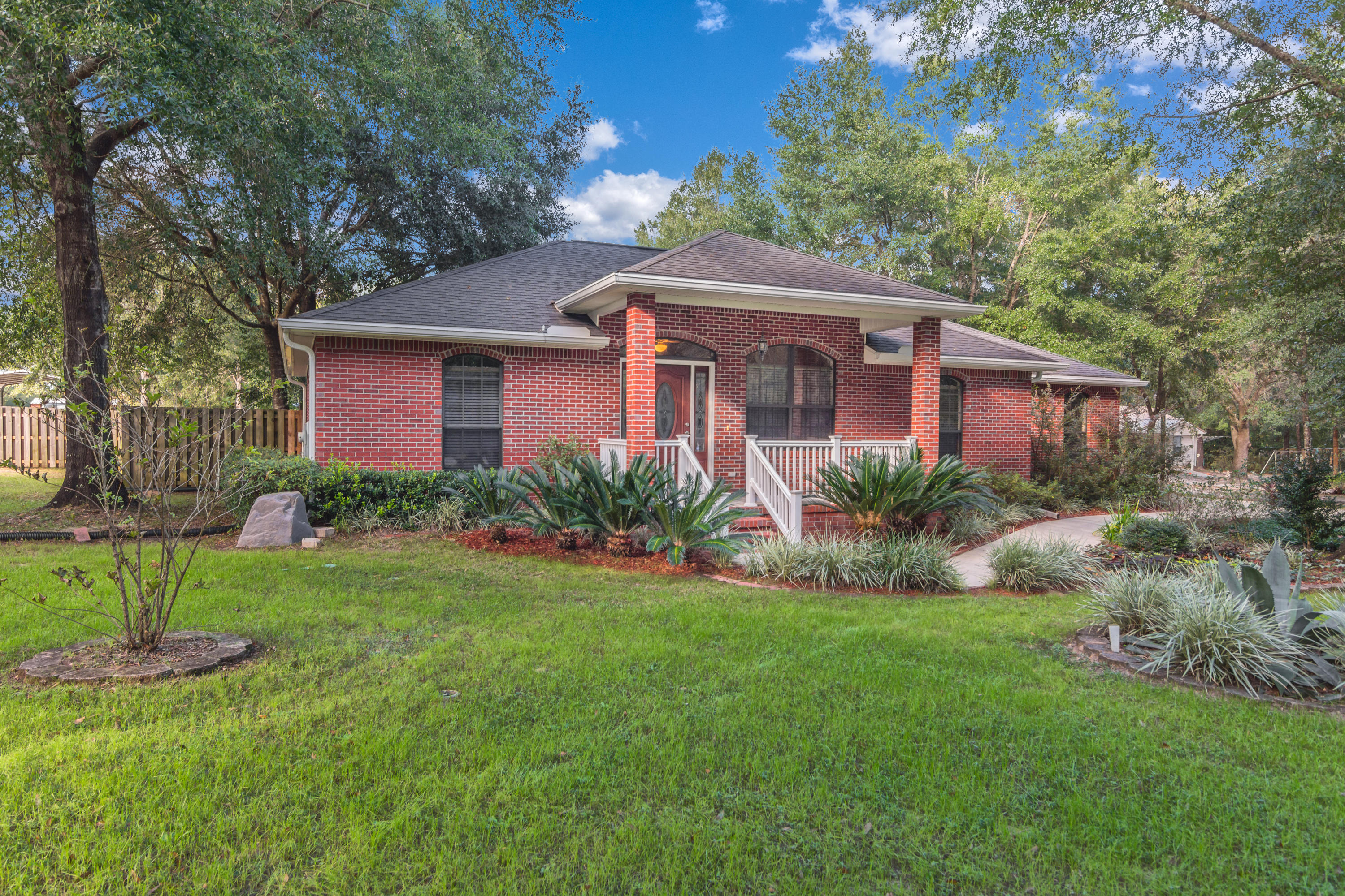 3811 Poverty Creek Road Crestview, FL 32539 - Photo 1 of 48 a front view of a house with a garden and trees