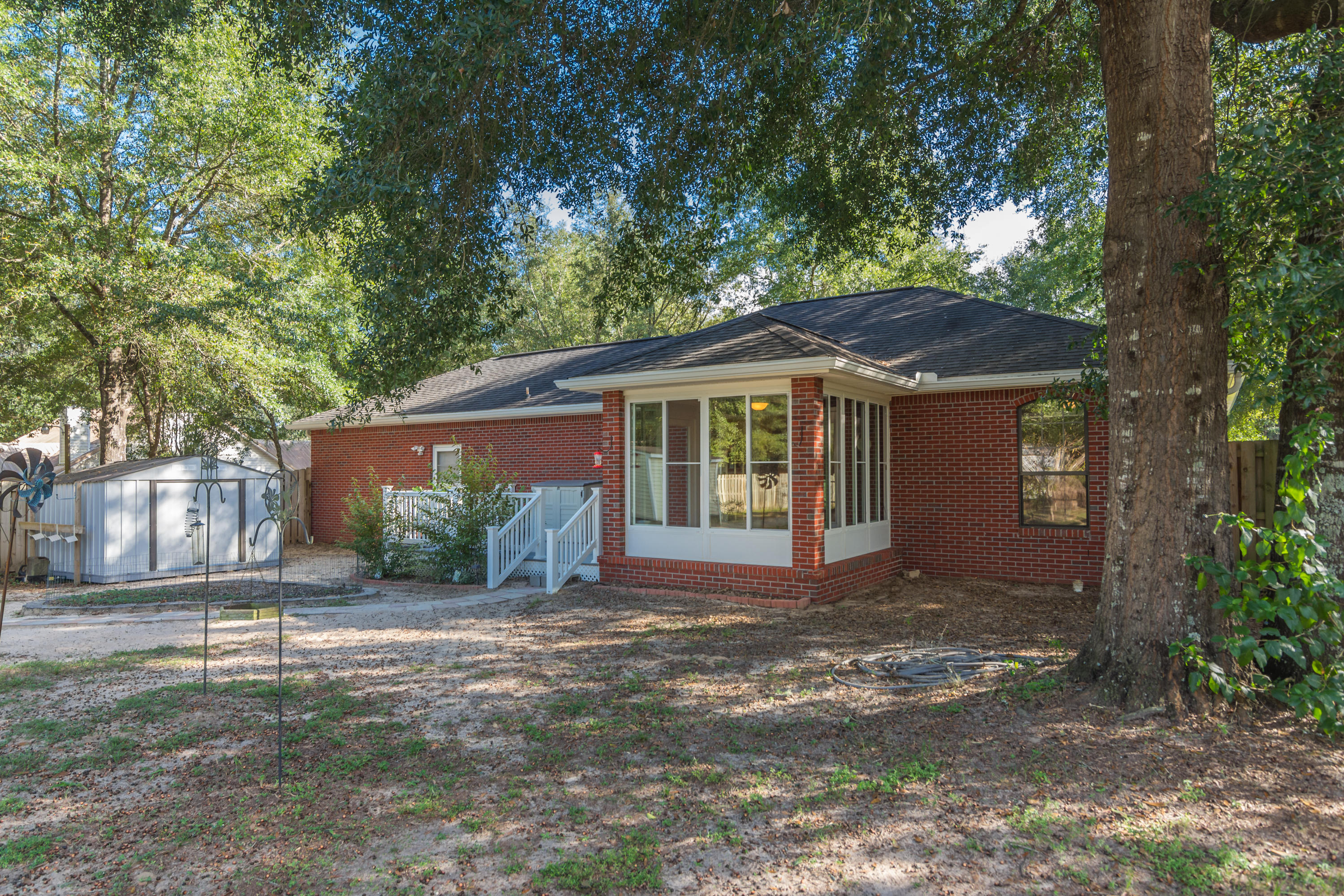 3811 Poverty Creek Road Crestview, FL 32539 - Photo 42 of 48 a front view of a house with a garden and trees