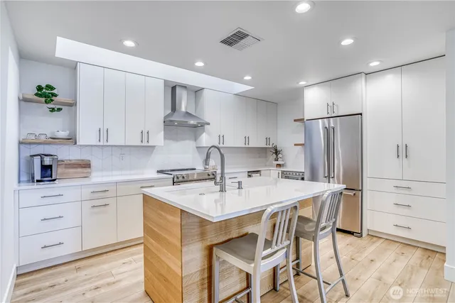 a kitchen with a white center island cabinets and stainless steel appliances