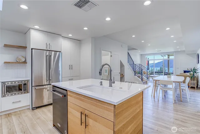 a kitchen with a sink refrigerator and chairs