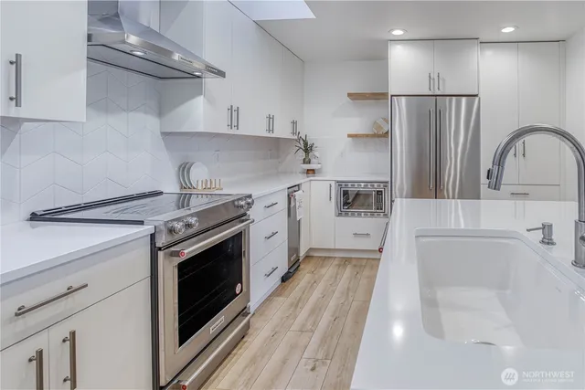 a kitchen with stainless steel appliances a stove a sink and a refrigerator