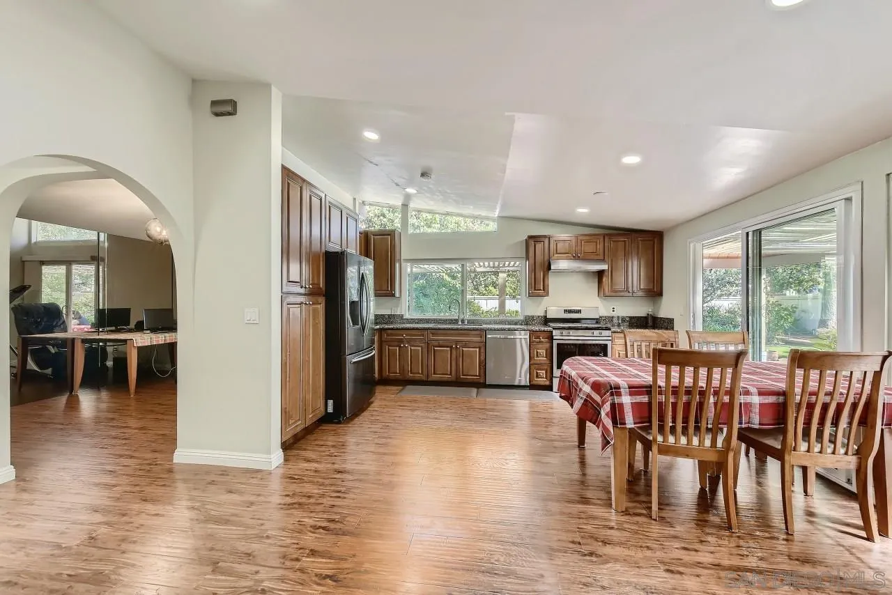13847 Tobiasson Road Poway, CA 92064 - Photo 6 of 28 a kitchen with stainless steel appliances a dining table chairs and wooden floor