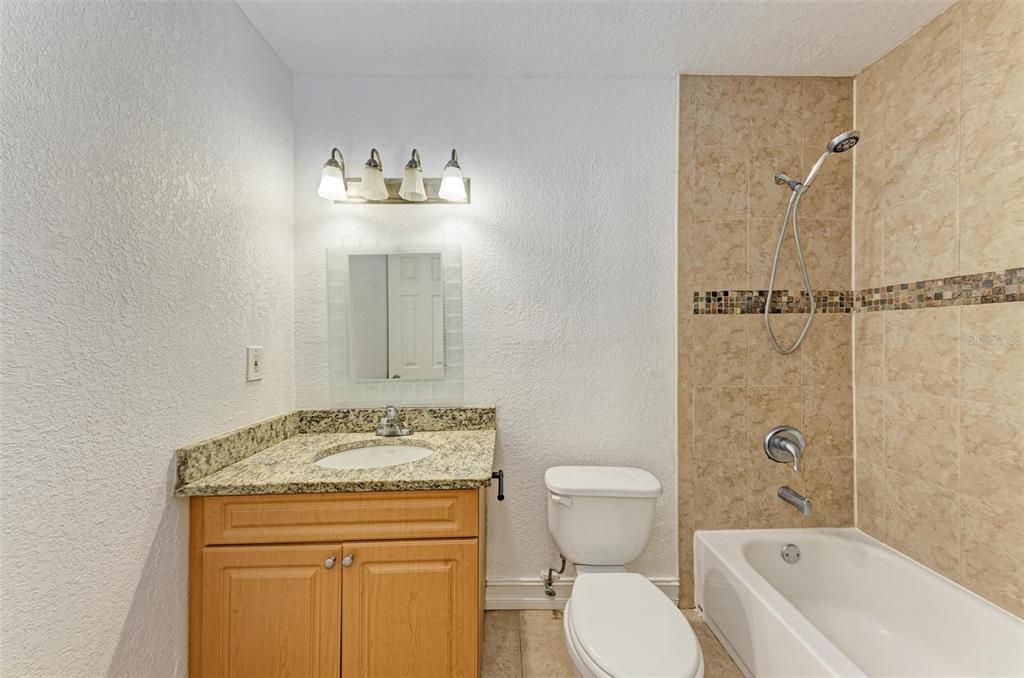 3411 Clark Road, Unit 212 Sarasota, FL 34231 - Photo 17 of 20 a bathroom with a granite countertop sink a toilet and shower