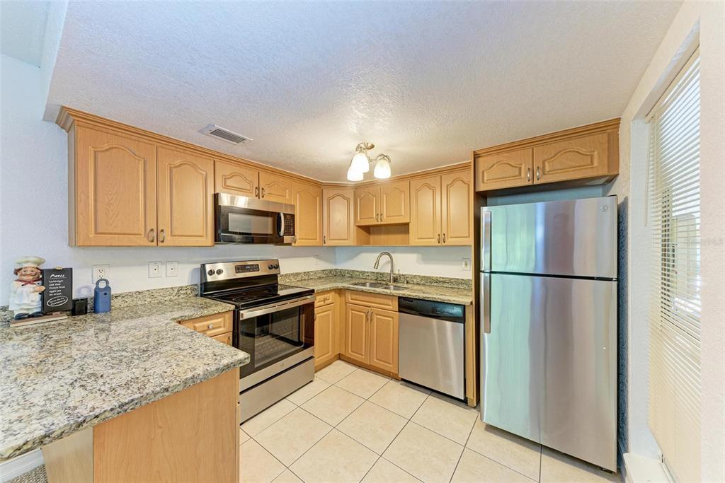 3411 Clark Road, Unit 212 Sarasota, FL 34231 - Photo 10 of 20 a kitchen with stainless steel appliances granite countertop a refrigerator sink and stove