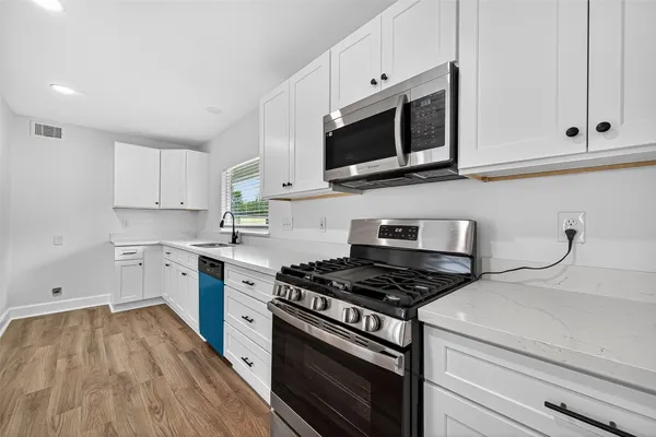 a kitchen with cabinets stainless steel appliances and wooden floor