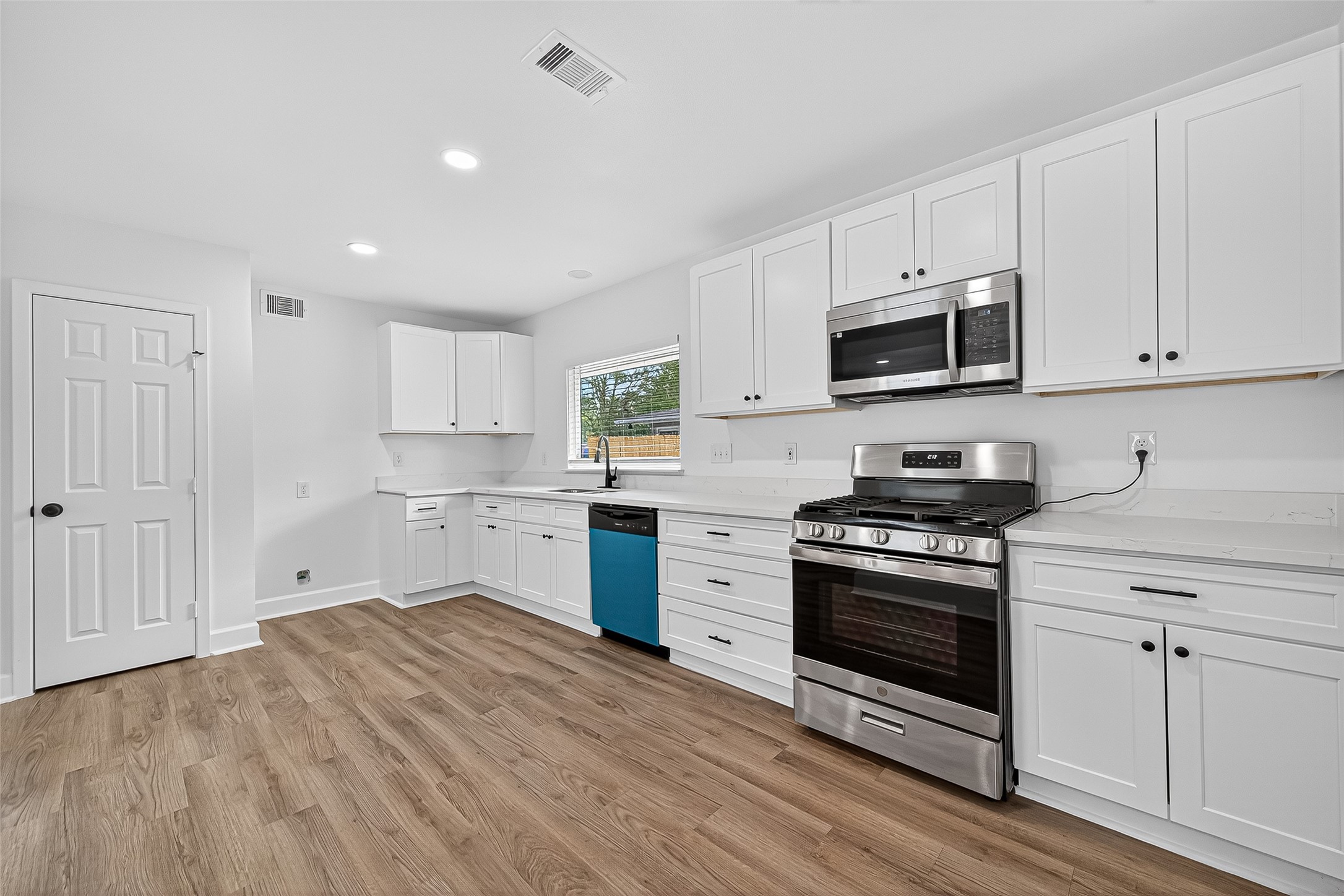 1609 North Pacific Street Conroe, TX 77301 - Photo 12 of 28 a kitchen with granite countertop a stove a sink and a microwave