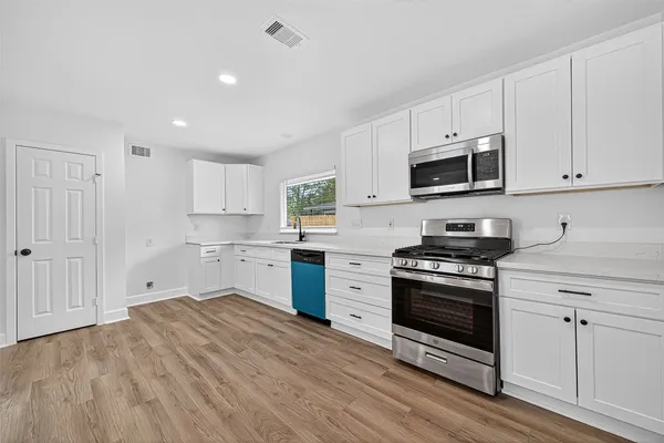 a kitchen with granite countertop a stove a sink and a microwave