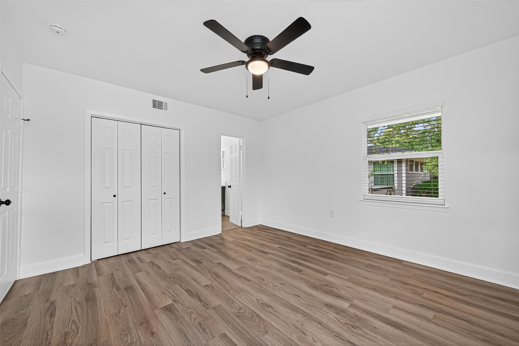 1609 North Pacific Street Conroe, TX 77301 - Photo 15 of 28 a view of an empty room with wooden floor and a ceiling fan